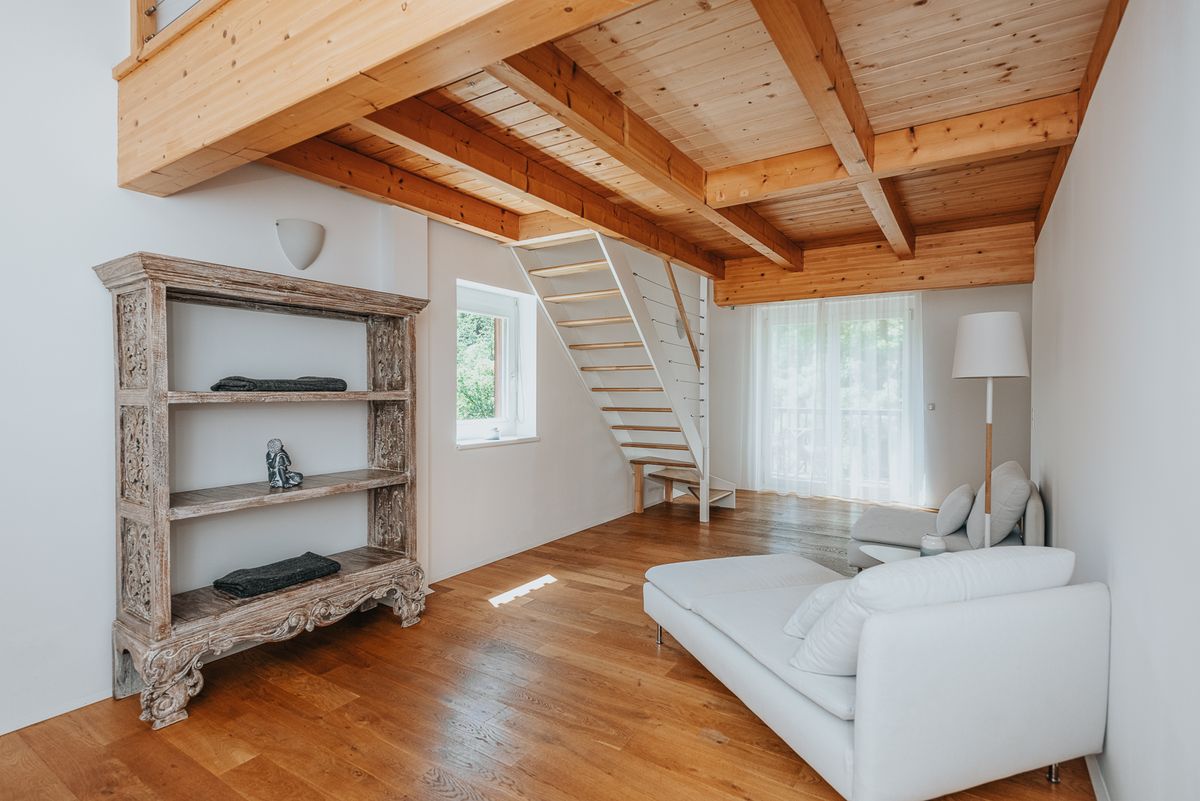 Wohnraum der Ferienwohnung mit Holzdecke und Treppe zur Galerie